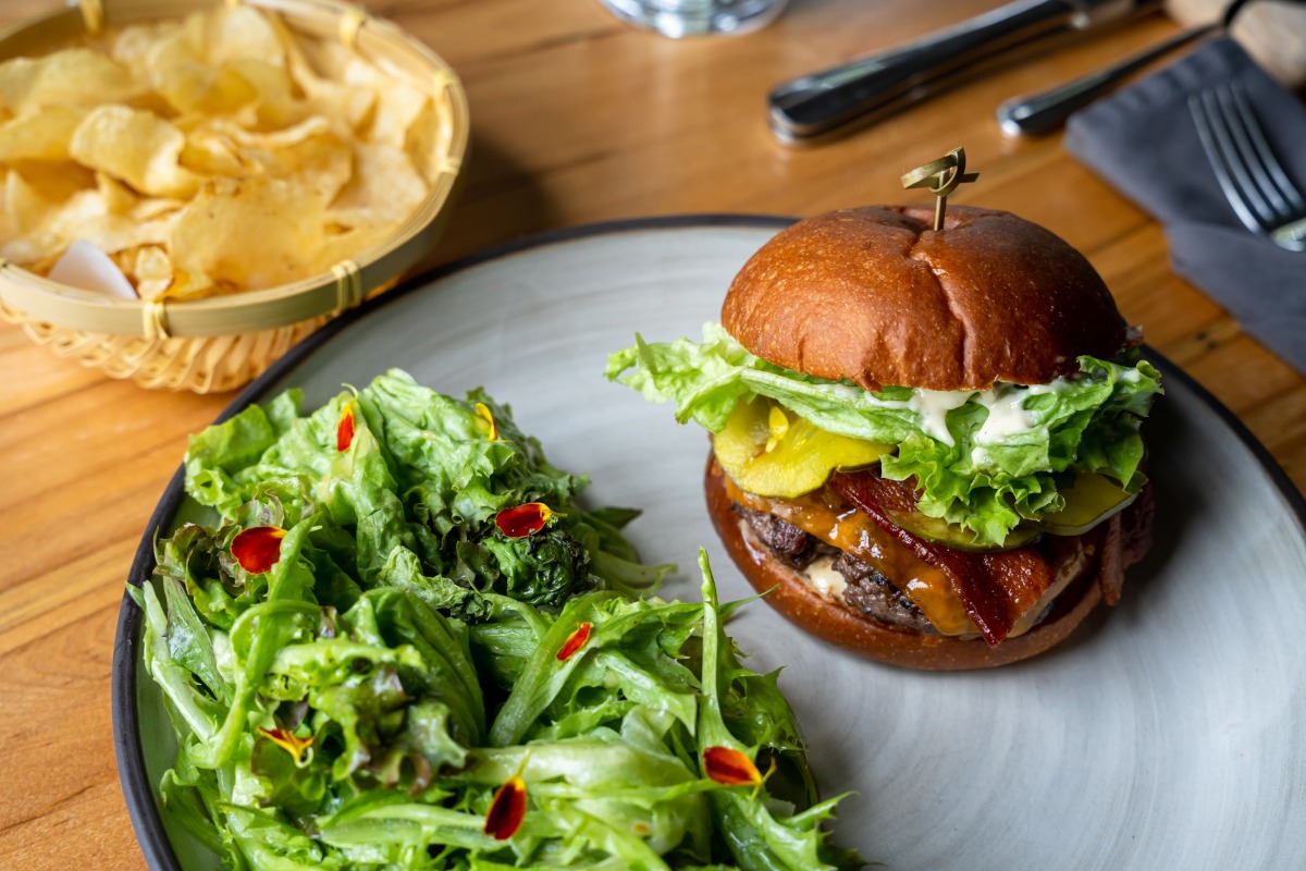 Burger with a mixed green salad and a bowl of chips